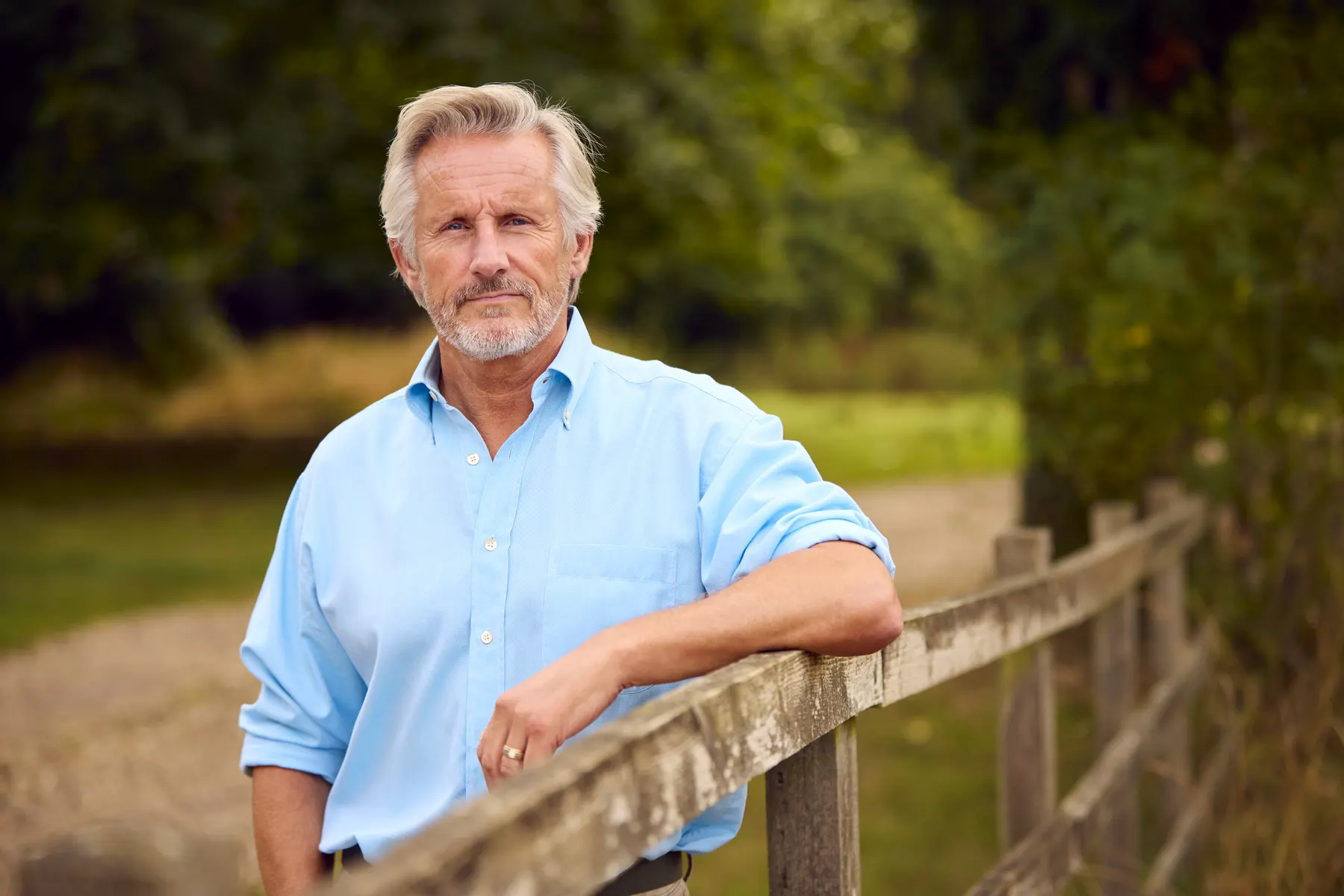 Your local agent leaning on a farm fence